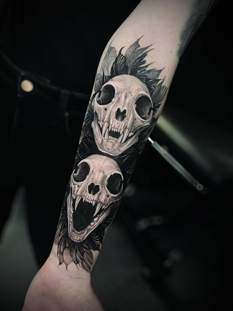 A black and grey tattoo of two cat skulls. Done by one of our Bristol tattoo artists at No Regrets.
