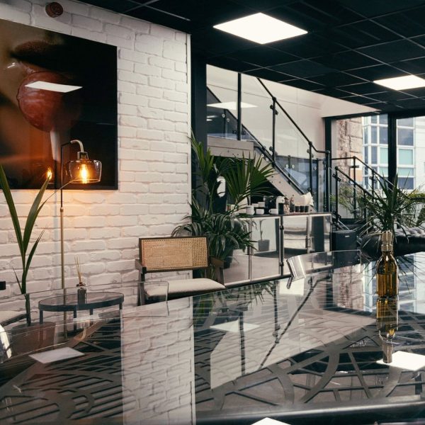 Reception area at No Regrets Manchester. A glass table is in the foreground with photography on a white brick wall and stairs in the background.