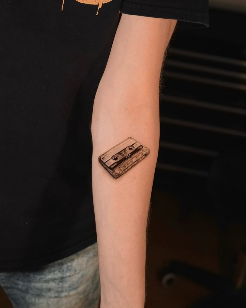 A micro realism tattoo of a cassette tape by Bugra at No Regrets Miami