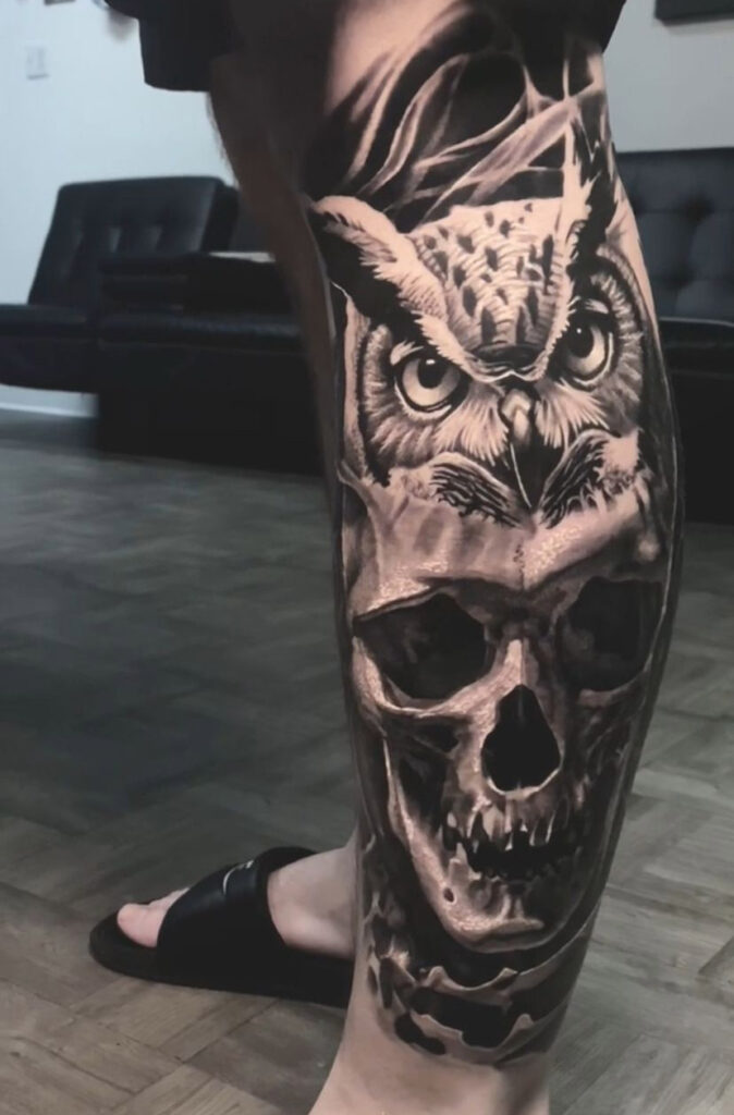 A skull and owl black and grey leg tattoo by Ruben Jackson