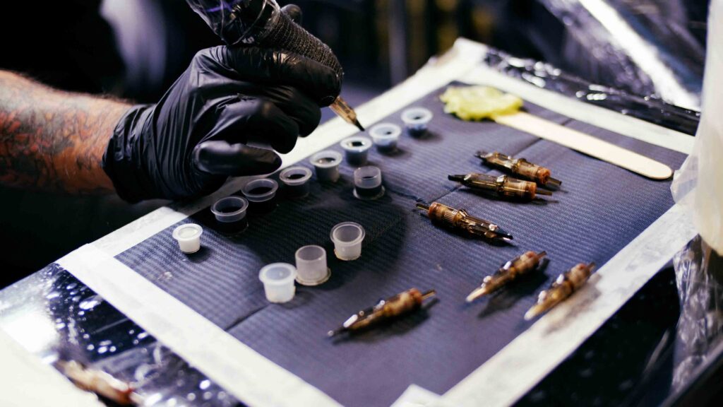 A tattoo artists clean organises station set up showing ink pots and various tattoo needles. 
