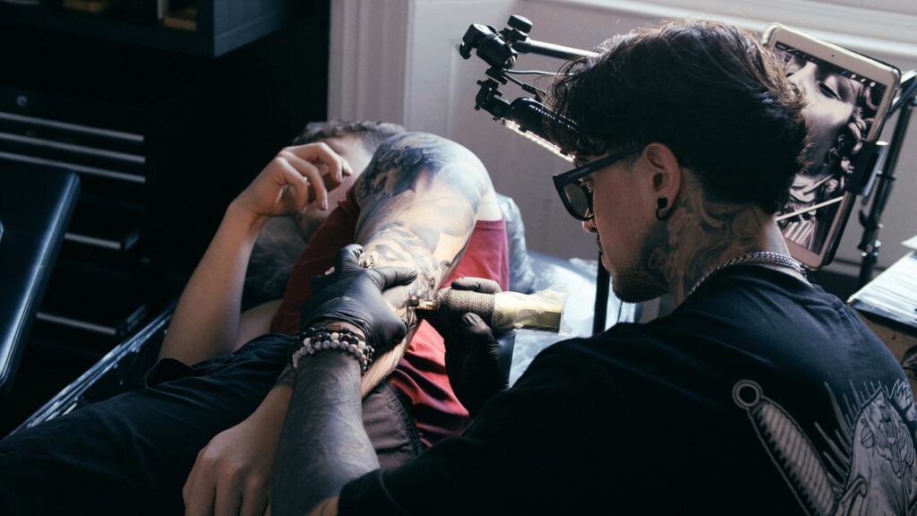 A tattoo artist works on a clients elbow 