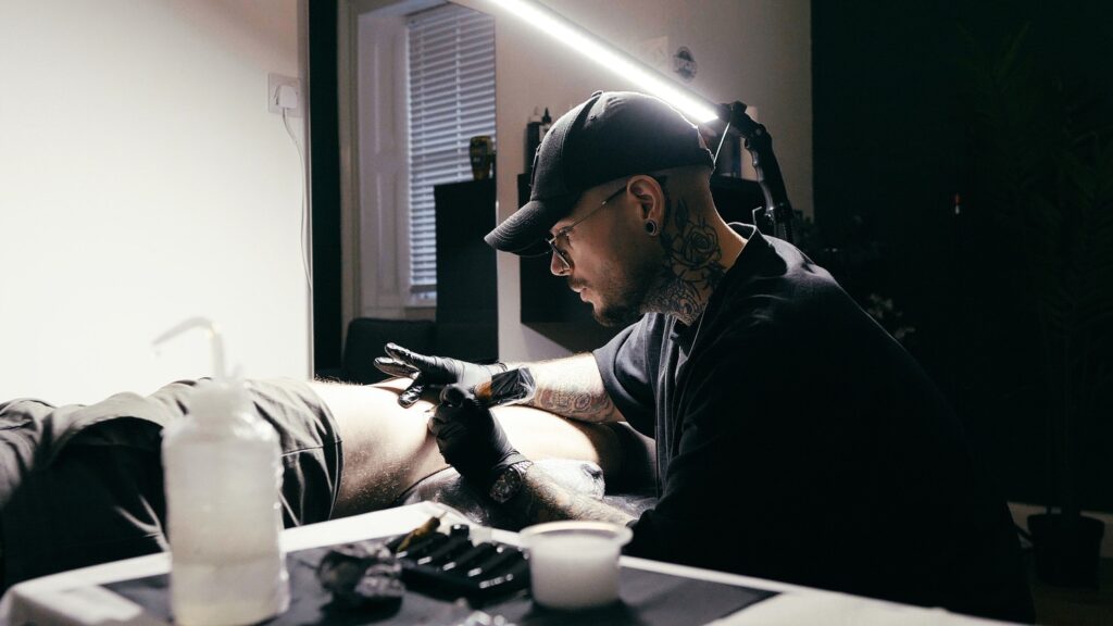Bugra, a male tattoo artist tattoos a client at No Regrets Studios