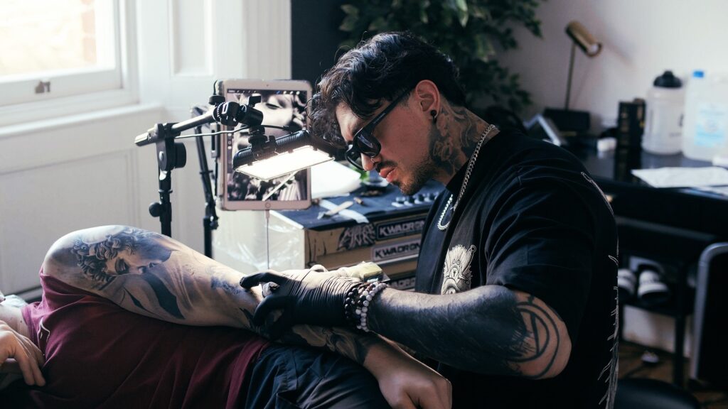 Andy Ramos, a tattoo artist at No Regrets Studios tattoos a clients arm. 